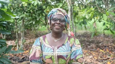 TANON GOUMAN THÉRÈSE EPSE Siéto fixant l&#x27;objectif alors qu&#x27;elle est dans une plantation de cacaoyers