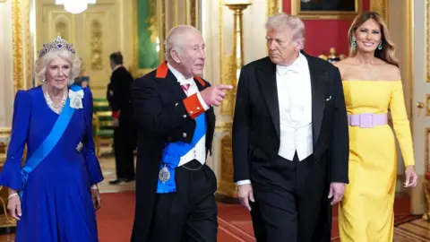 The Queen, King, Donald and Melania Trump walk through the Great Hall wearing smart clothes while talking and pointing as they attend the banquet portion of the first day of Trump&#x27;s state visit, at Windsor Castle on Wednesday.