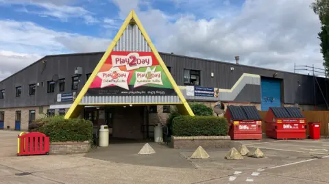 The outside of an industrial unit which is where Play2Day is based. A sign is above the entrance which says Play2Day on it.