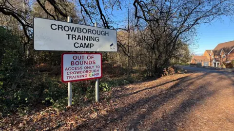 A leaf-covered path with a sign for &#x27;Crowborough Training Camp&#x27;.
